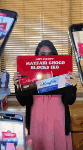 a woman holding a red sign that says meet our new mayfair choco blocks ikg