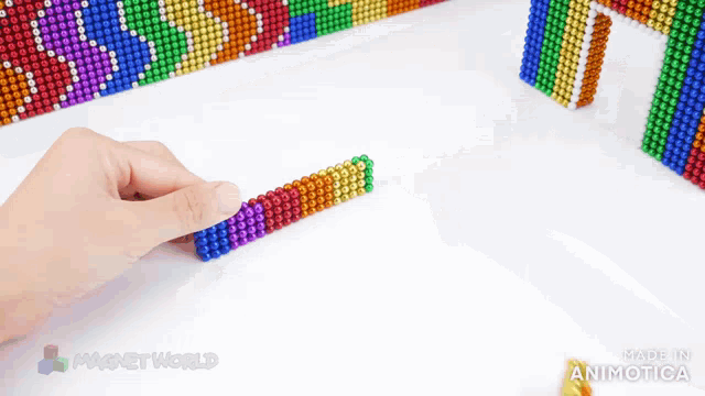 a person is playing with a rainbow colored set of magnet balls