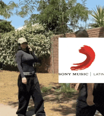 a woman talking on a cell phone in front of a sony music latin logo