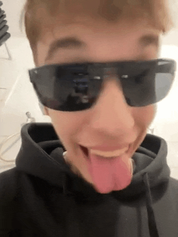 a man wearing sunglasses is sticking his tongue out .