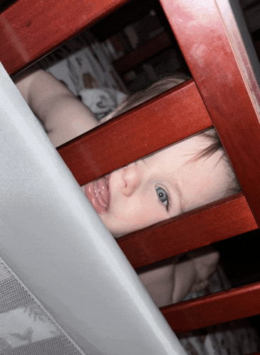 a baby laying in a wooden crib with a pacifier in her mouth