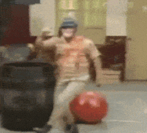 a man is standing next to a red ball in a room .