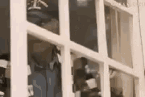 a closet with a lot of clothes in it and a reflection of a person in the window .