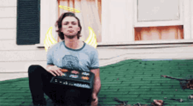 a man with angel wings is sitting on a green brick roof