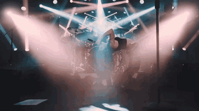 a man is doing a handstand on stage in front of a microphone