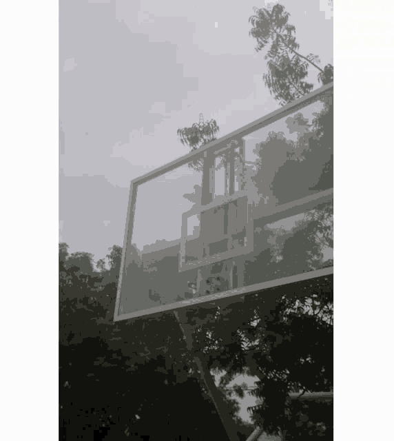 a clear basketball hoop with trees in the background and a cloudy sky