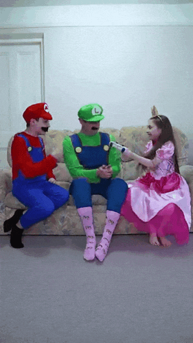 two men dressed as mario and luigi are sitting on a couch with a girl dressed as princess peach
