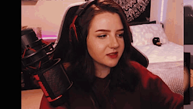 a girl wearing headphones and a red shirt is sitting in front of a microphone ..