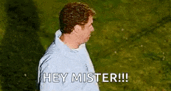 a man in a blue jacket is standing in the grass and says `` hey mister '' .