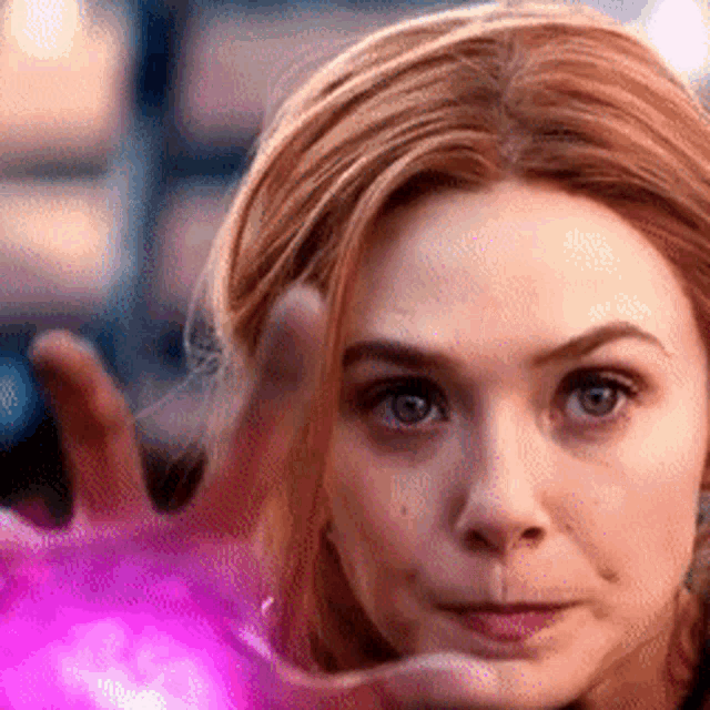 a close up of a woman 's face with a pink ball in her hand .
