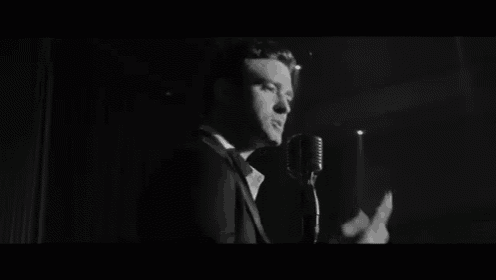 a man in a suit is singing into a microphone in a large room