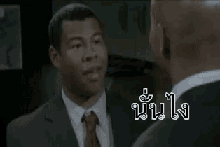 a man in a suit and tie is laughing with another man in a suit and tie