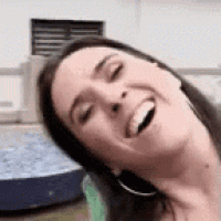a woman is smiling with her eyes closed and her mouth open while sitting on a couch .