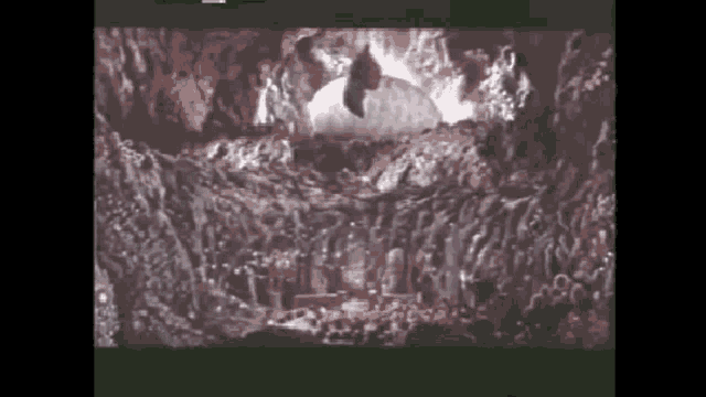 a group of people are gathered in a cave with a statue in the background .