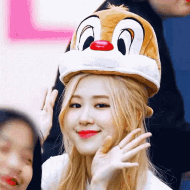 a woman wearing a dale the squirrel hat waves at the camera