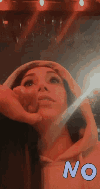 a woman wearing a pink hoodie is being touched by a man 's hand and the word no is above her
