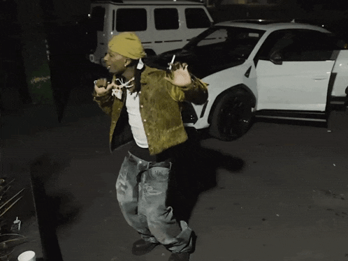 a man in a yellow beanie is standing in front of a white car