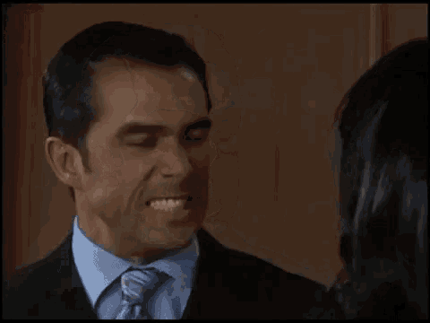 a man and a woman are looking at each other and the woman is smiling .