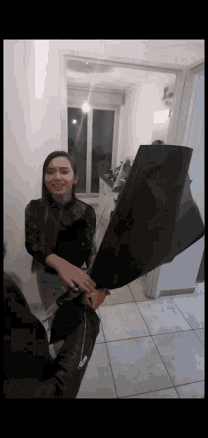a woman is holding a large black umbrella in a hallway