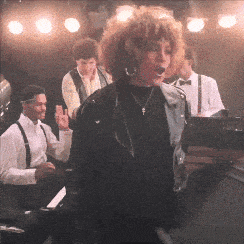 a woman in a black leather jacket is singing on stage