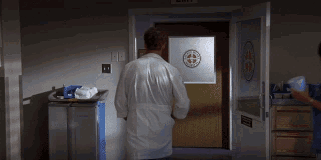 a man in a lab coat stands next to a nurse in front of a door that says exit