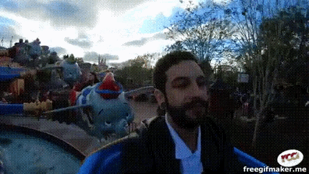 a man with a beard is riding a dumbo roller coaster at an amusement park