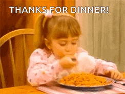 a little girl is sitting at a table eating a plate of spaghetti .