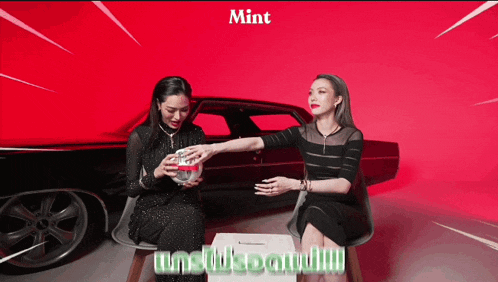 two women are sitting in front of a car with the word mint on the bottom