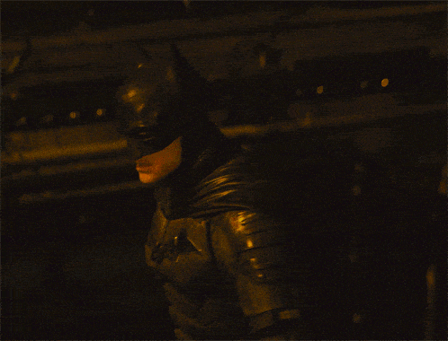 a man in a batman costume is standing in a dark room