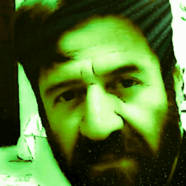 a close up of a man 's face with a beard and a green background