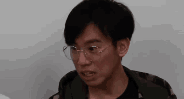 a young man wearing glasses is making a funny face and looking at the camera .