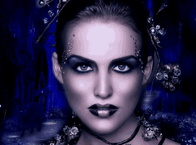 a close up of a woman 's face with dark makeup and gold lipstick