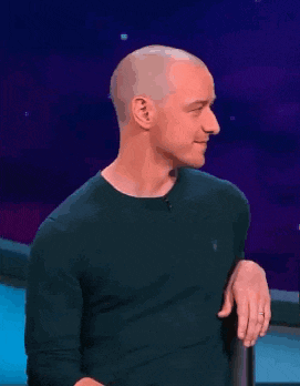 a man in a green shirt is laughing with his eyes closed and his hand in his pocket .