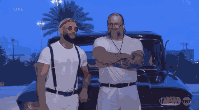 two men are standing in front of a car that says aew on it