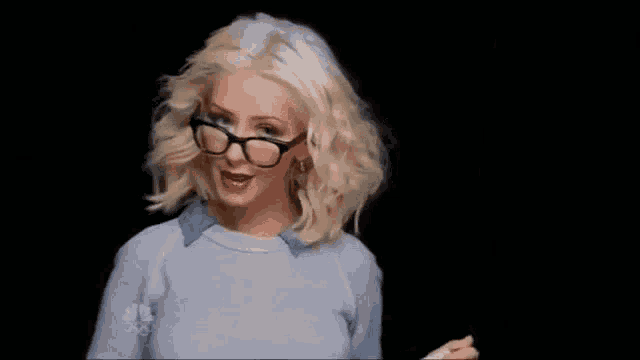 a woman wearing glasses and a blue shirt is holding a piece of paper .