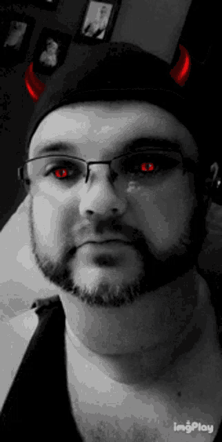 a man with a beard and red eyes is wearing a hat with horns .