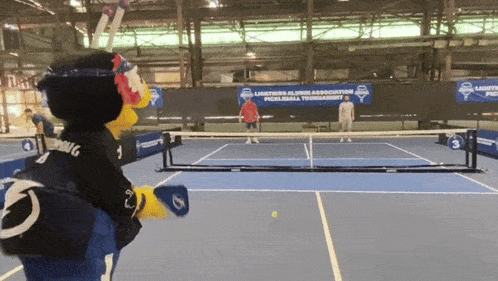 a mascot on a tennis court with a banner that says lightning alumni association
