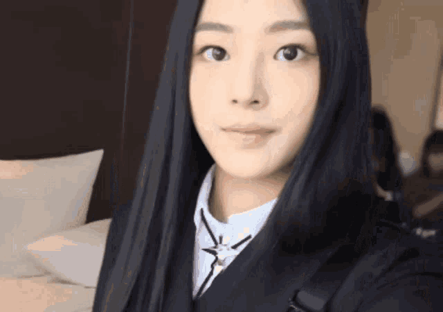 a woman with long black hair is wearing a school uniform and looking at the camera