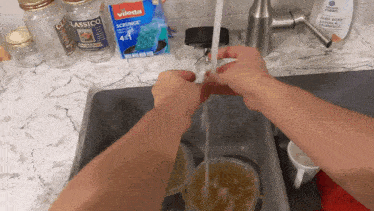 a person is using a vileda sponge to clean a glass jar