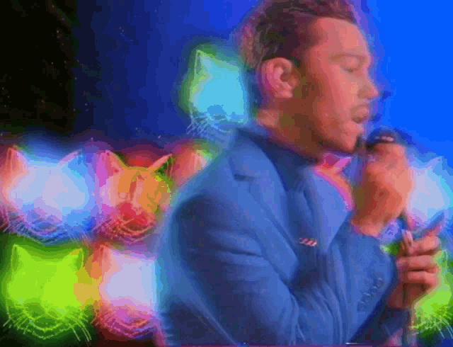 a man in a blue suit singing into a microphone with a cat in the background
