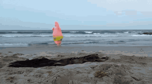 patrick star from spongebob is standing on a sandy beach