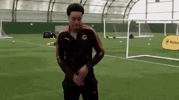 a man is standing on a soccer field with his hands on his hips