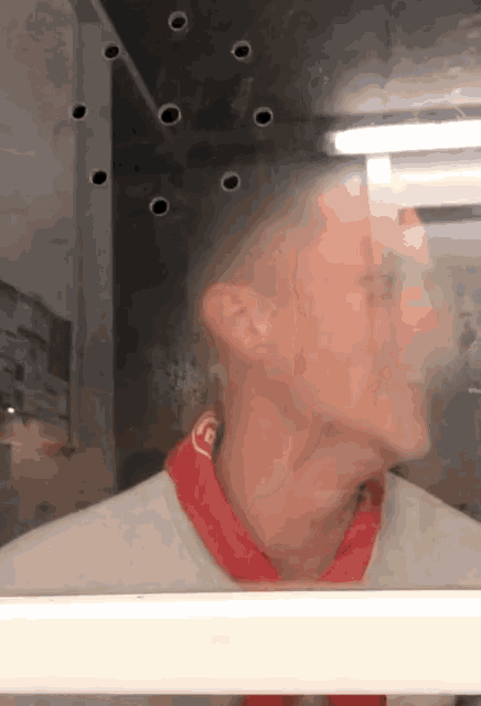 a man wearing a red scarf with the letter f on it looks at himself in a mirror