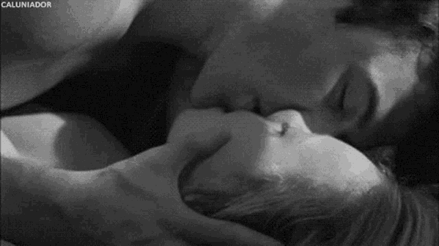 a black and white photo of a man and a woman kissing .