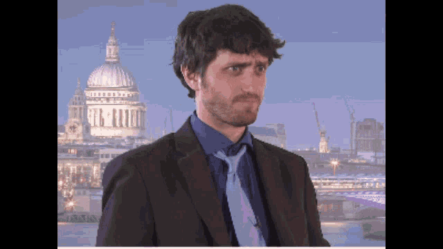 a man in a suit and tie is standing in front of a city skyline