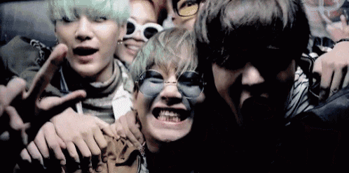 a group of young men are posing for a picture while wearing sunglasses .