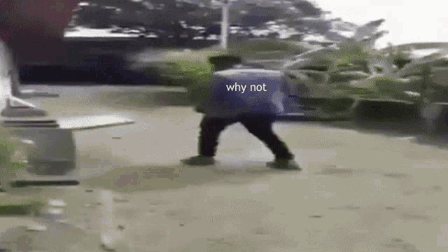 a man is walking down a street with a bag on his back and the words `` why not '' written on the ground .
