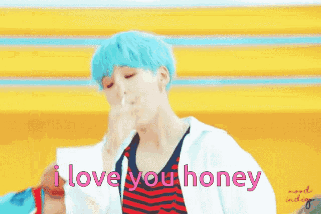 a boy with blue hair is dancing in front of a yellow background with the words `` i love you honey '' written on it .