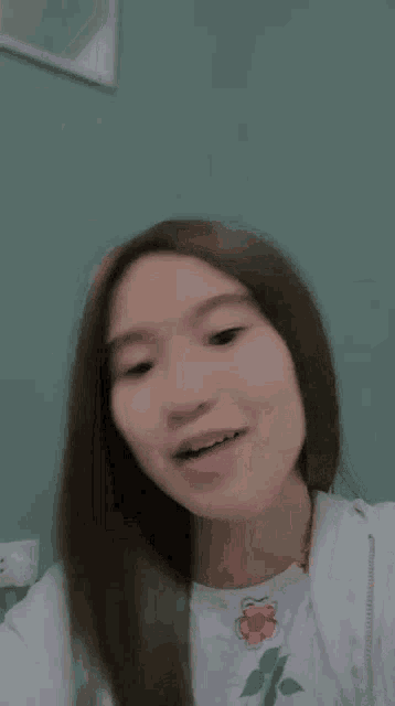 a young woman with long hair is making a funny face while wearing a white shirt .