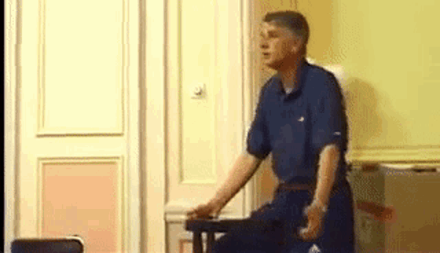 a man in a blue shirt is standing in front of a door